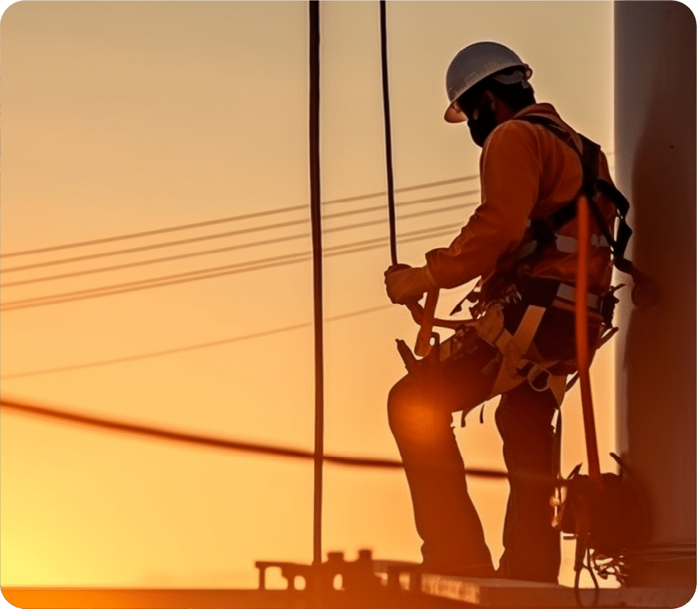 Worker installing new electricity wire while sun sets in background